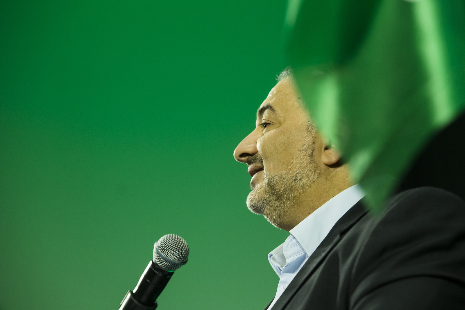 A politician giving a speech against a green backdrop