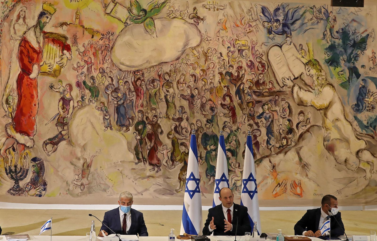 Three politicians sit under an enormous Chagall painting