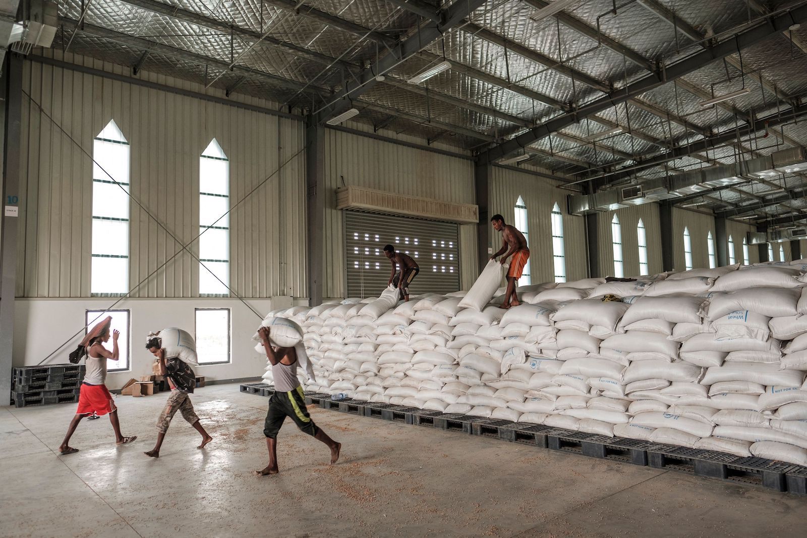Men carry sacks of food at a warehouse