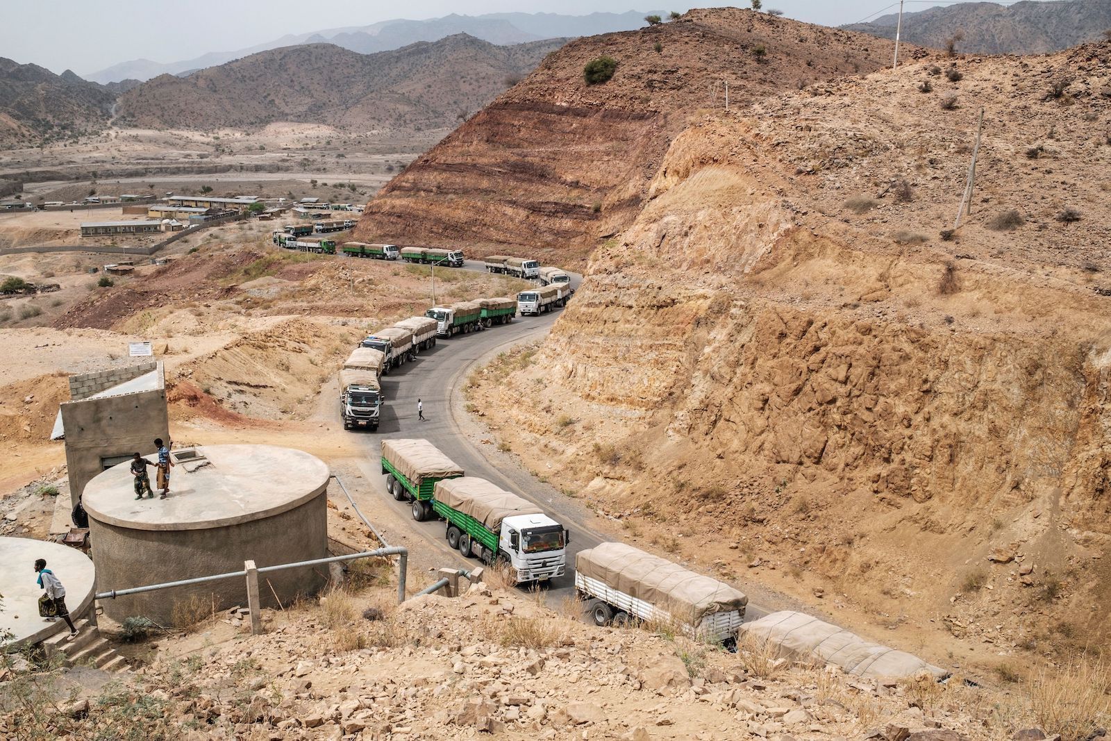 A caravan of trucks wind through a desert landscape