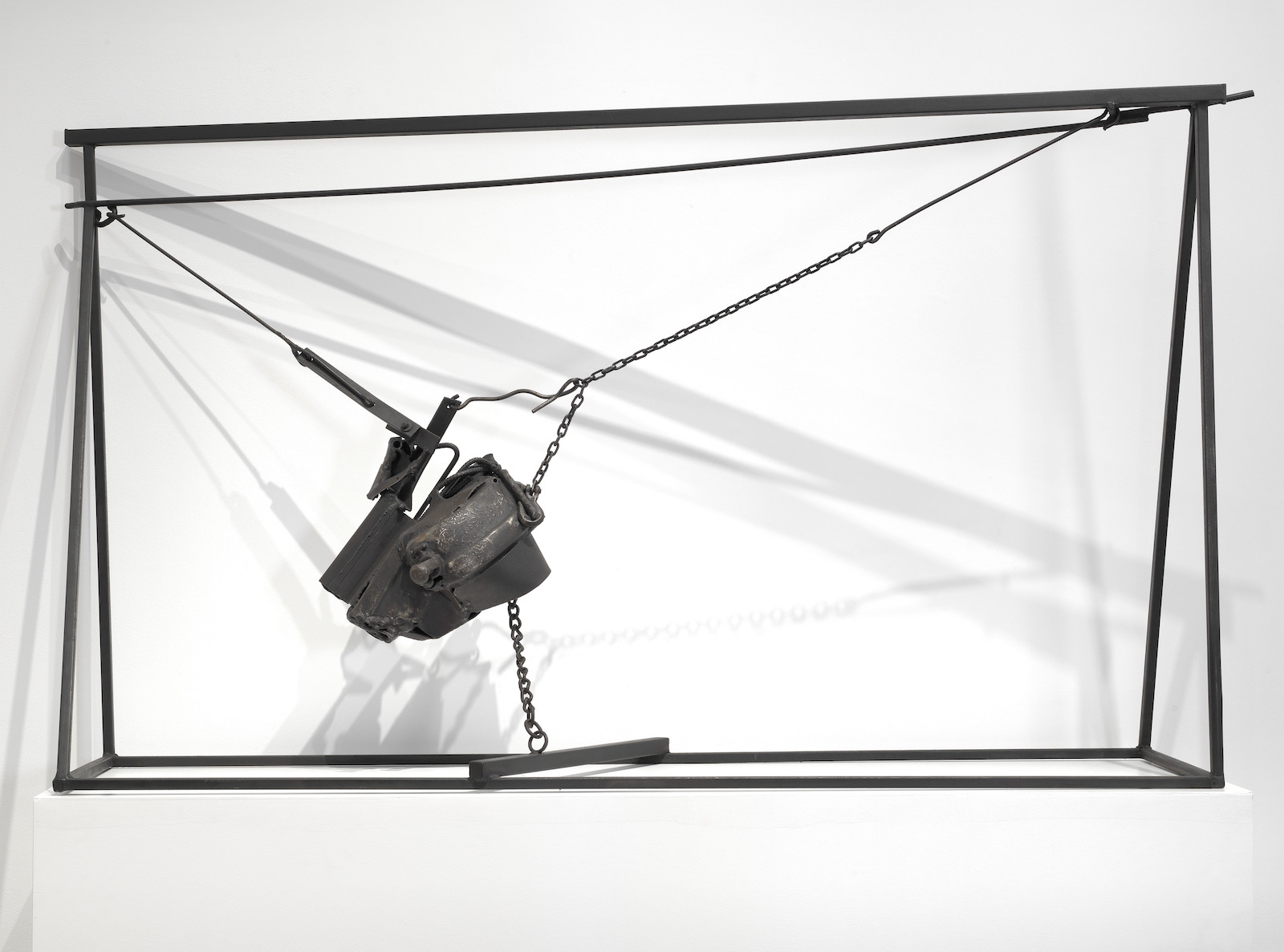 A sculpture in which several welded-together pieces of steel hang suspended between a wire and a chain