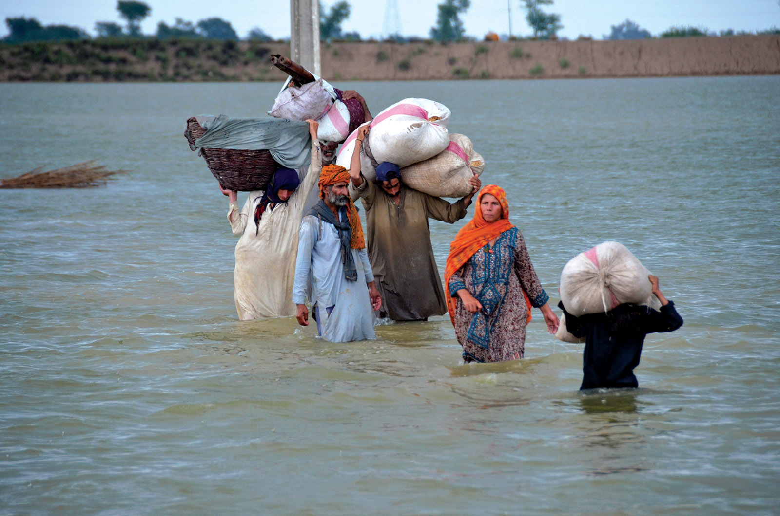 A displaced family wading through floodwaters, Jafarabad, Pakistan
