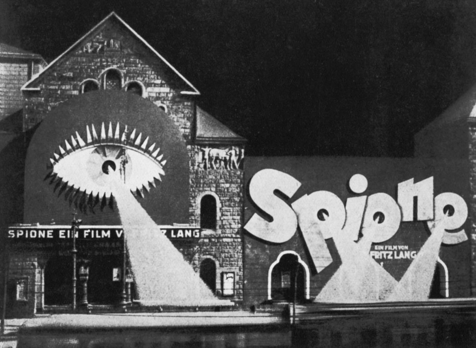 A movie theater facade bedecked with a mural of a giant eyeball with a spotlight emerging from the pupil