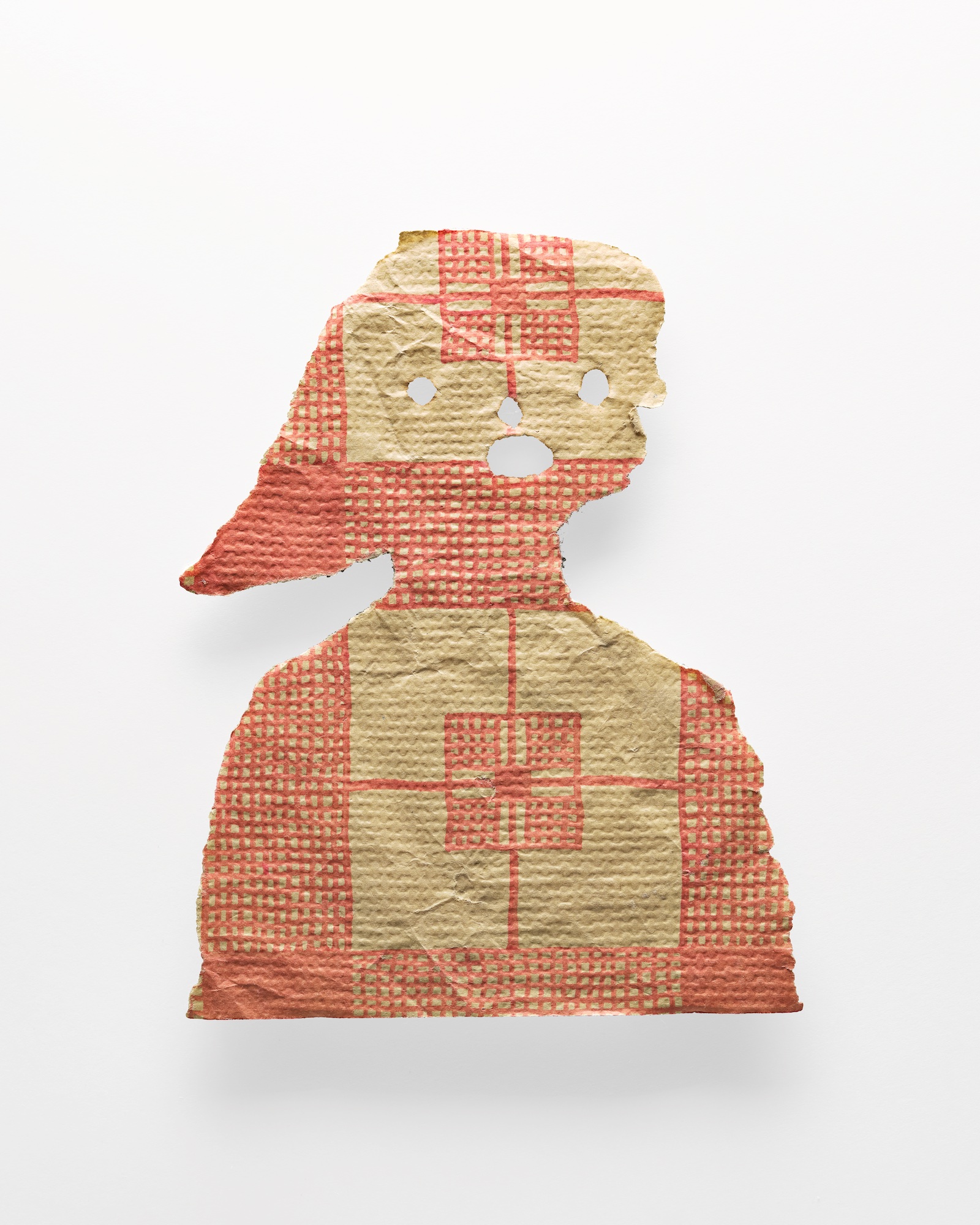 A cutout of a girl's head and face on red and yellow tablecloth material
