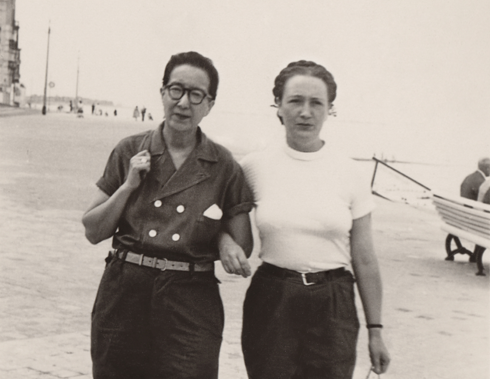 Two women walking down a beach, arm in arm