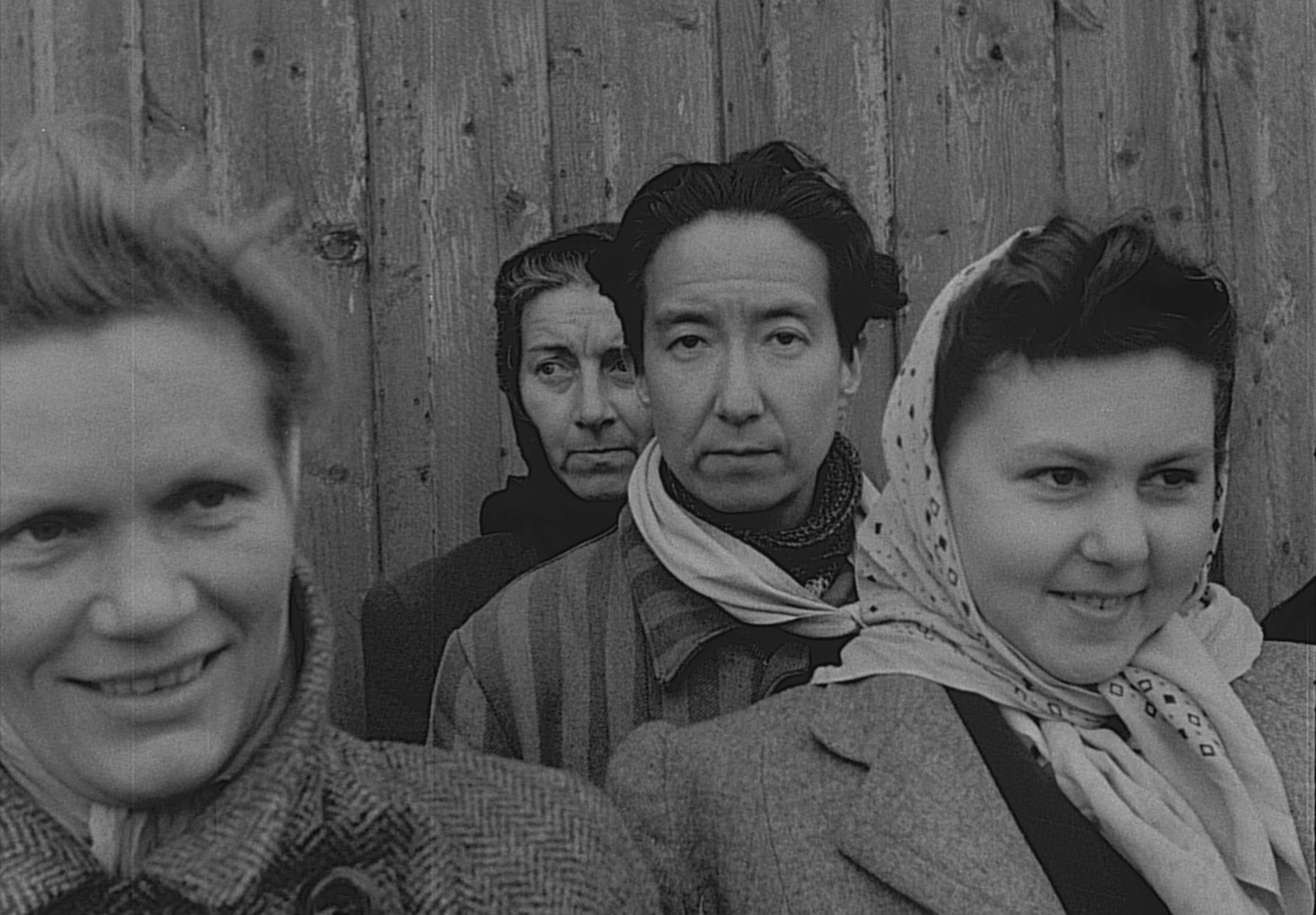 A black-and-white photo of four women, three looking elsewhere and one, at center, staring directly at the camera