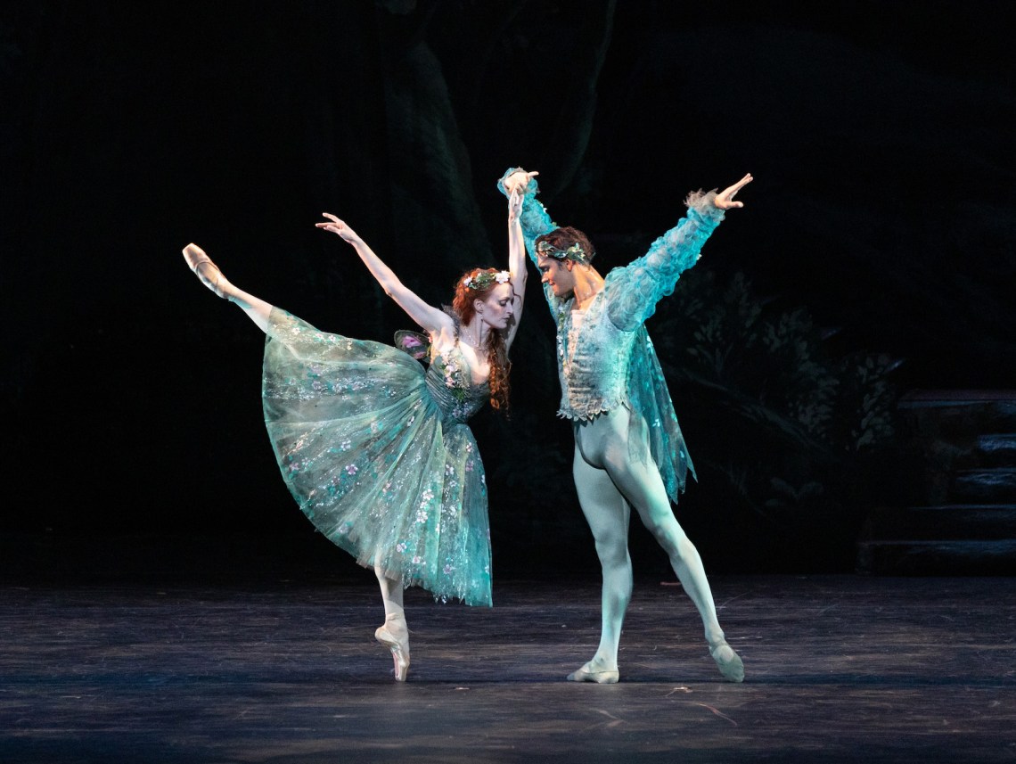 Two ballet dancers on a dark stage, wearing turquoise