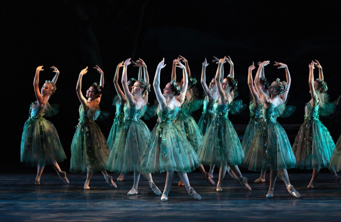 A group of ballet dancers wearing turquoise on a dark stage