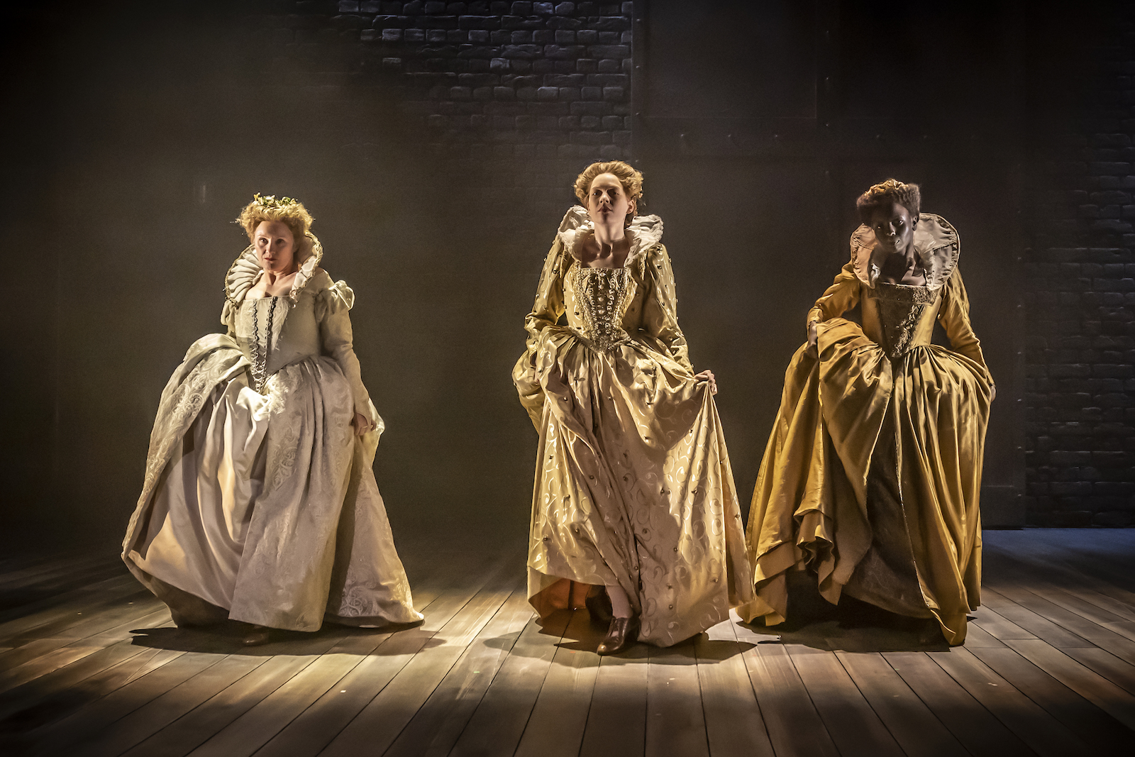 Three people in Elizabethan dress, spotlit on a stage