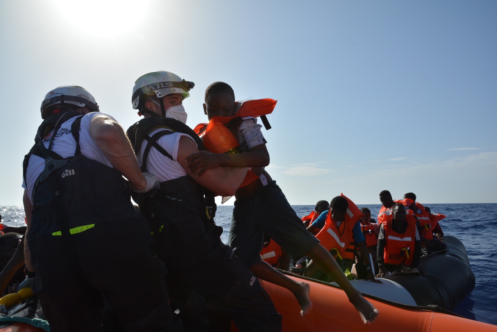 A man lifting a young child off a boat during a rescue at sea