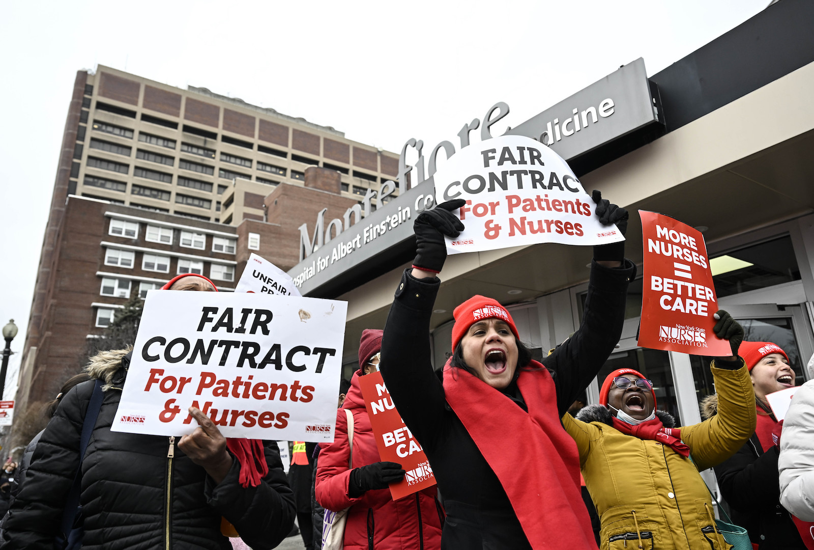 People on a picket line holding up signs that read FAIR CONTRACT For Patients & Nurses and MORE NURSES = BETTER CARE