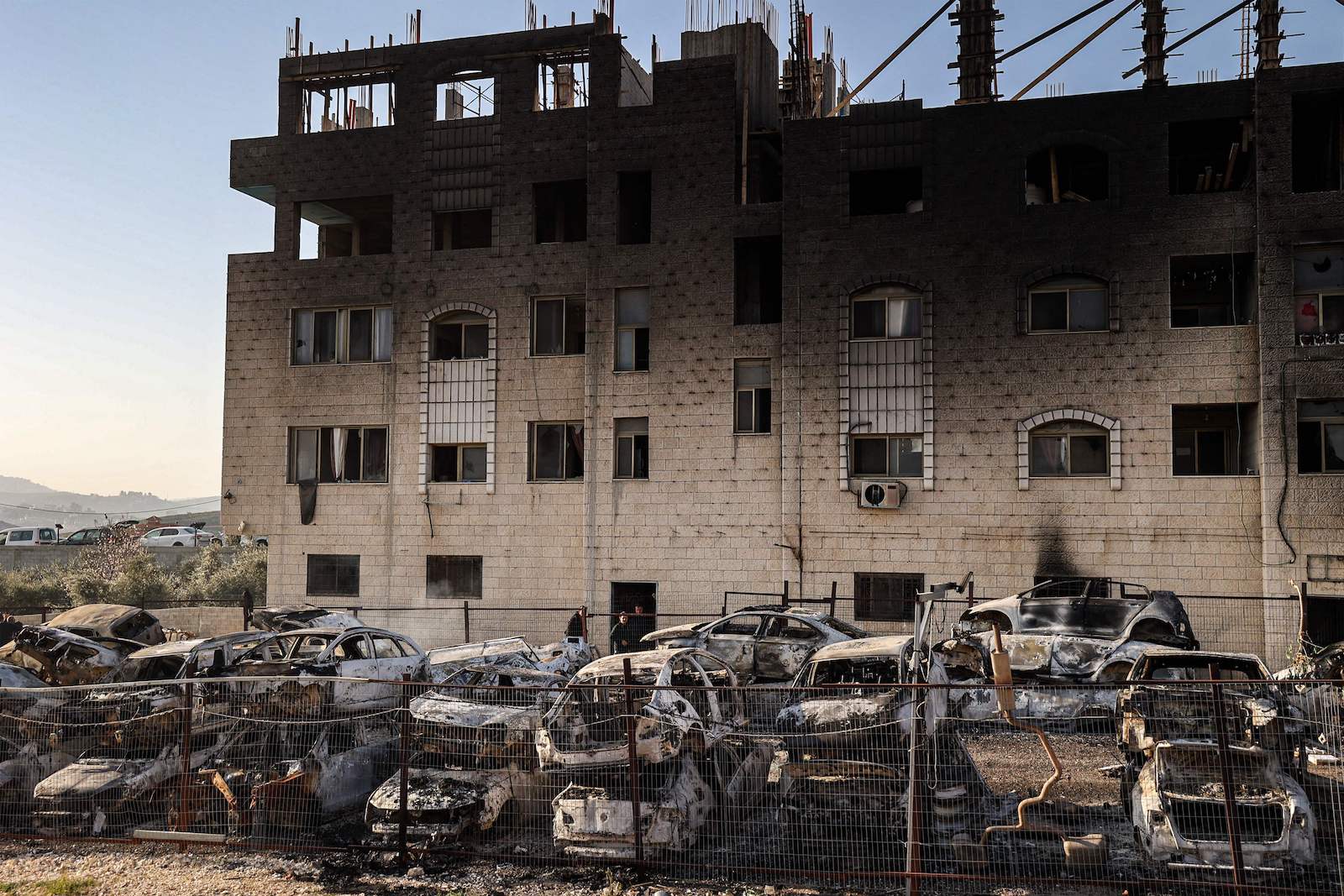 The charred ruins of a building surrounded by burnt-out cars