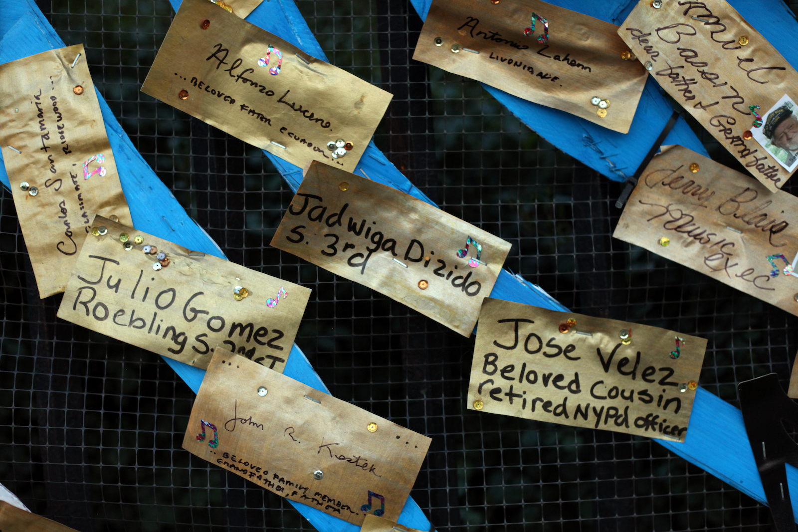 Names on brown paper attached to blue streamers: Jadwiga Dizido, Jose Velez, beloved cousin retired NYPD officer, Julio Gomez