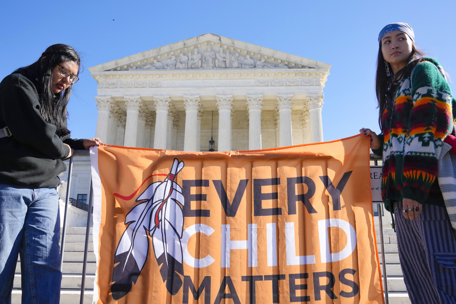 Demonstrators holding up a sign in front of the Supreme Court building saying "EVERY CHILD MATTERS"