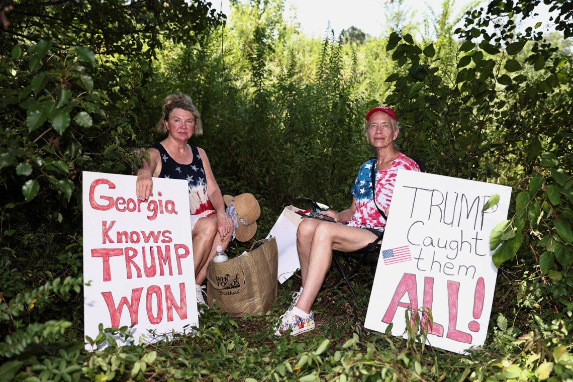 Supporters of Donald Trump with signs near Fulton County Jail on the day he was booked on state charges for his efforts to overturn the 2020 election