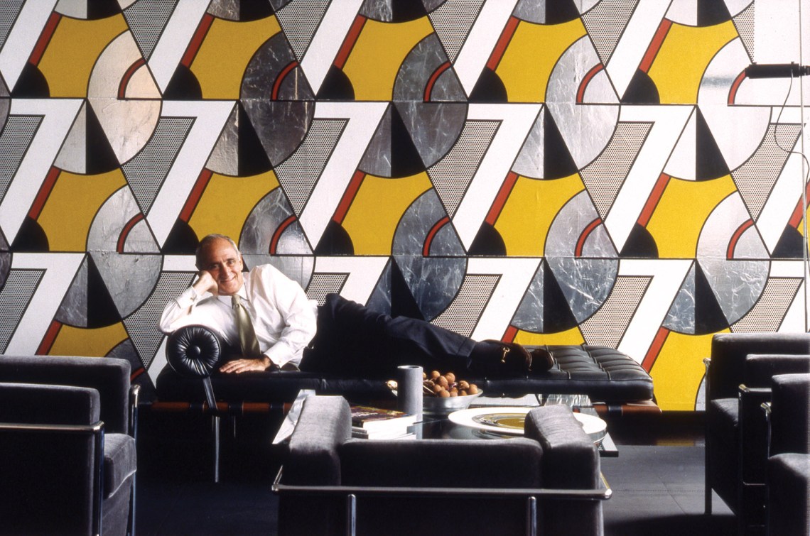 Robert A.M. Stern on a Mies van der Rohe chaise longue in front of Roy Lichtenstein’s vinyl wall covering Modern Banner,