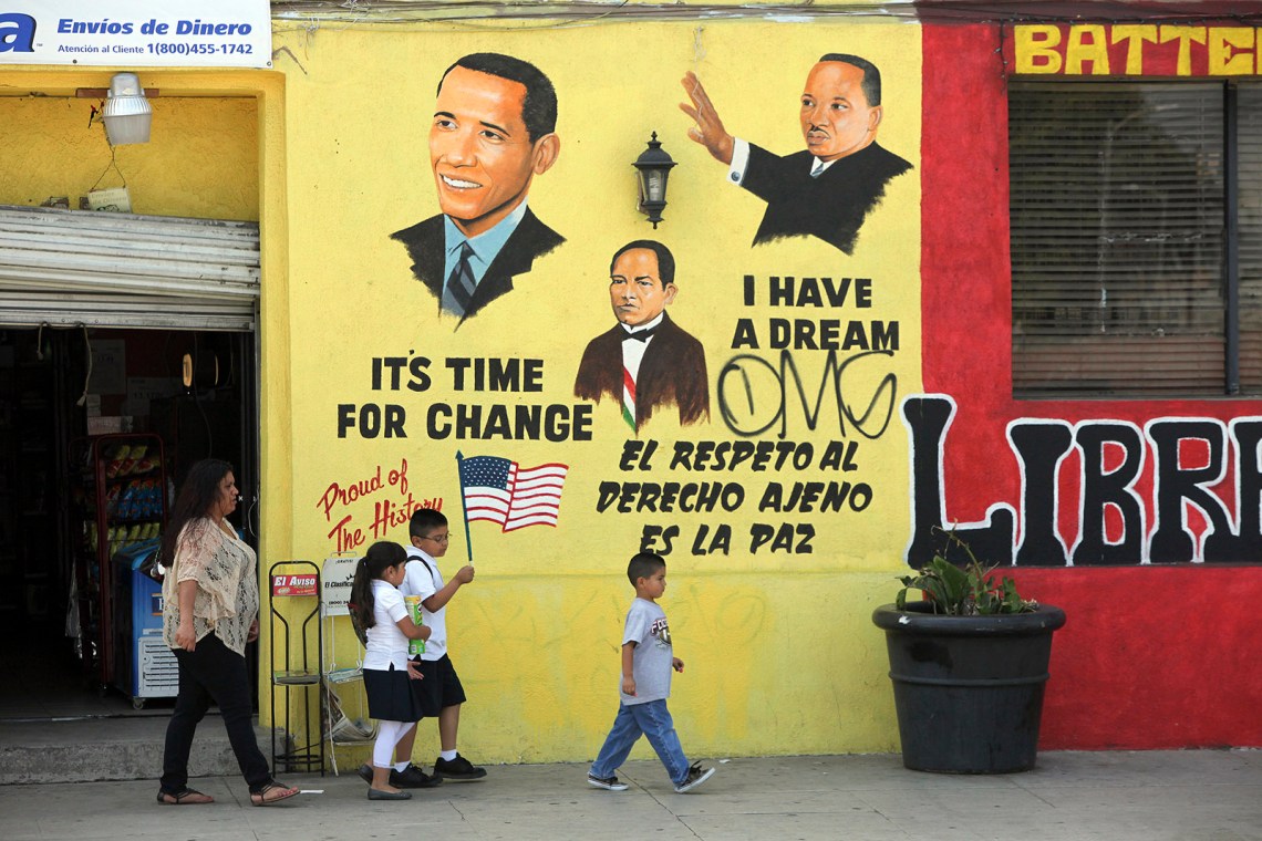 A family of Angelenos walking past a mural celebrating Barack Obama, former Mexican president Benito Juárez, and Martin Luther King Jr., South Los Angeles